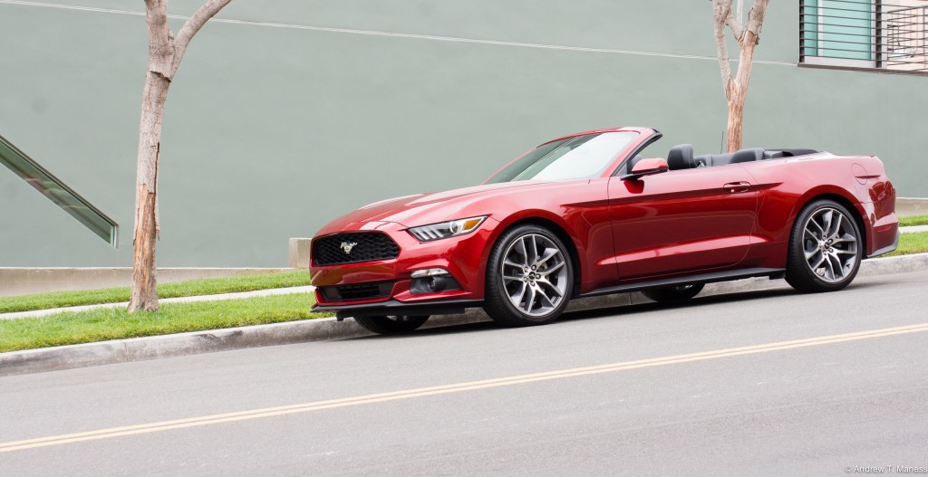 A Cherry Red Ford Mustang convertible parked on the street.